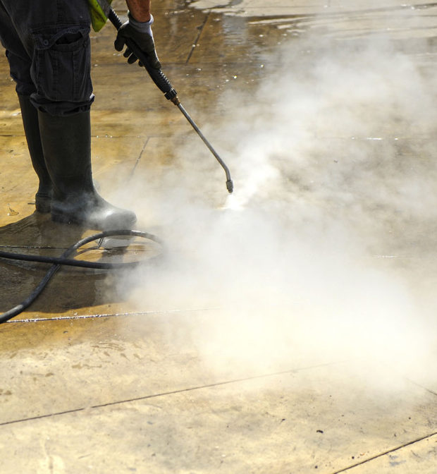 Worker cleaning with pressurized water the pavement